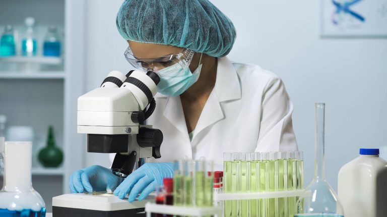 Woman scientist looking into microscope, biochemical research, cosmetology